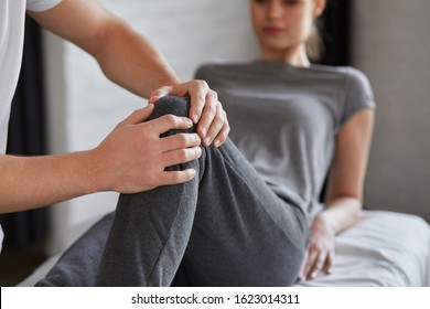 Female patient doing physical exercises with physiotherapist. Male therapist treating injured knee of young athlete.Post traumatic rehabilitation, sport physical therapy, recovery concept. - Powered by Shutterstock