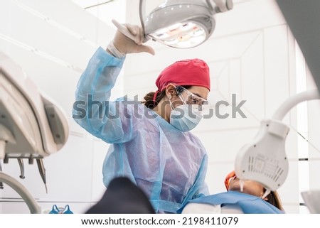 Female patient during check up in dental clinic. The dentist is wearing face mask and protective glasses.