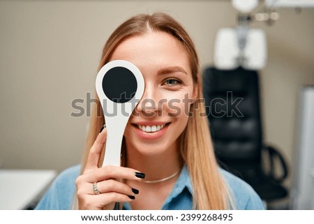 A female patient is having her eyesight checked in an ophthalmology clinic with one eye closed. Ophthalmology and vision testing concept.