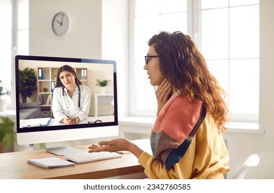 Female patient having online medical consultation via video call on computer. Young woman sitting in front of screen, talking to remote doctor and asking advice about sore throat. Telemedicine concept - Powered by Shutterstock