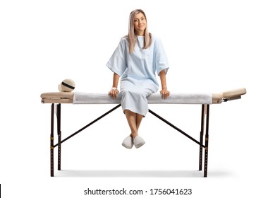 Female Patient In A Hospital Gown Sitting On A Medical Bed Isolated On White Background 