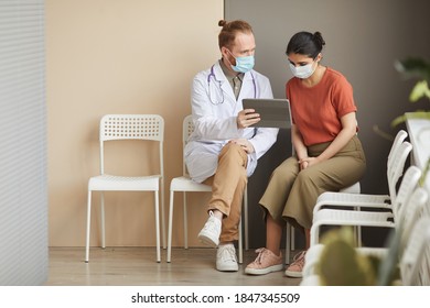 Female Patient Looking At Monitor Of Digital Tablet While Doctor Showing Her The Way Of Treatment Sitting At The Corridor At Hospital