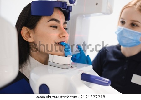 Female patient make a dental computer tomograph. The radiologist makes a CT scan of the jaw. Woman taking panoramic x-ray of teeth in clinic
