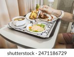 Female patient ready to eat healthy meal with varied menu served on hospital bed