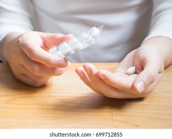 Female Patient Taking Medicine And Holding Blister Pack With White Tablet On Hands. Close Up Of Young Hands Taking Pill Out From Packaging At Home. Health Care And Medical Treatment Concept.