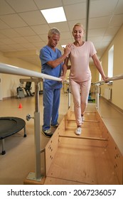 Female Patient Uses Parallel Bars To Walk In Rehab Center