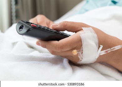 Female Patient watching TV and remote control in hand In Hospital Bed