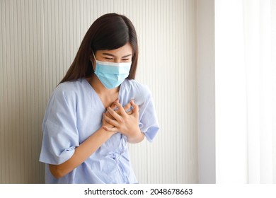 female patient wearing a mask have heart pain Put your hand on your chest to reduce the pain. Cardiovascular disease in working women aged 35 years and over. Hospital concept. medical services