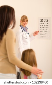 Female Pediatrician Ophthalmologist Child Pointing At Eye Chart Medical Office