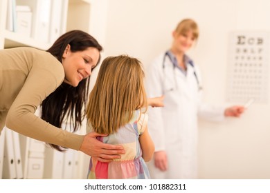 Female Pediatrician Pointing At Eye Chart Mother And Child Visit