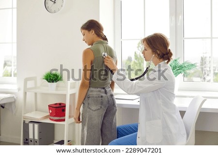 Female pediatrician using stethoscope checks lungs and heartbeat of preteen schoolgirl during medical examination. Child undergoes professional medical examination by doctor. Concept of medicine.