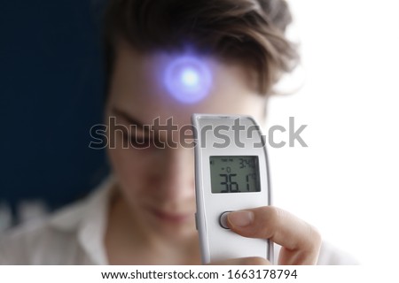 A female person being measured body temperature with a contactless thermometer