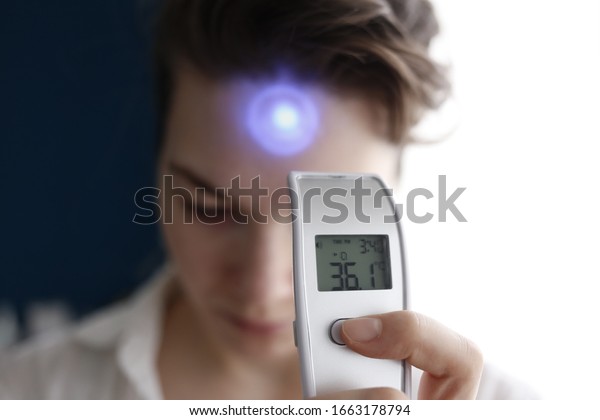A female person being measured body\
temperature with a contactless\
thermometer
