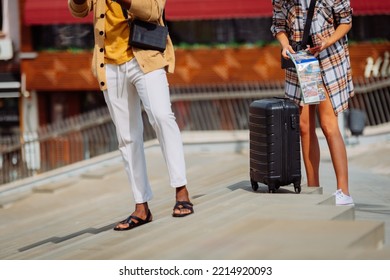 A Female Person Is Folding Up Her Map While Her Male Friend Is Taking A Pictures