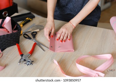 Female person making pink leather wallet with tools at atelier. Concept of handicraft business and fashionable accessories. - Powered by Shutterstock