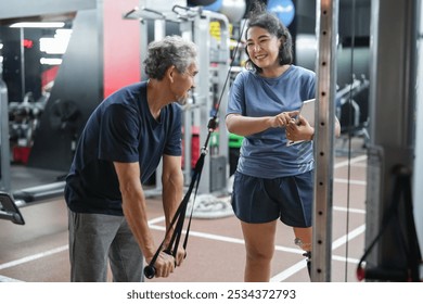 A female person with prosthetic leg,using digital tablet,training and giving advice a senior man to exercise at gym,healthy athlete with artificial leg trainer,working in gym - Powered by Shutterstock