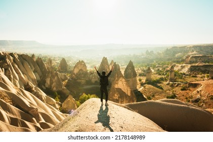 Female Person Stand With Hands Up Over Dramatic Valley On Hazy Sunrise With Fairy Chimneys Background. Solo Exploration In Turkey. Cinematic Travel Destination-Cappadocia 2020.