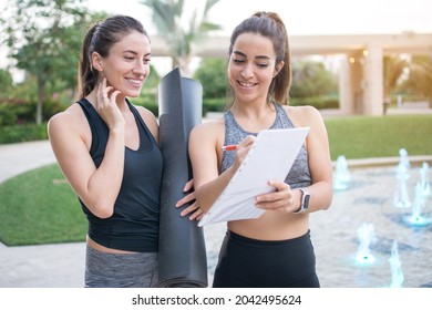 Female Personal fitness instructor showing fitness progress to her client after outdoor exercise class. - Powered by Shutterstock