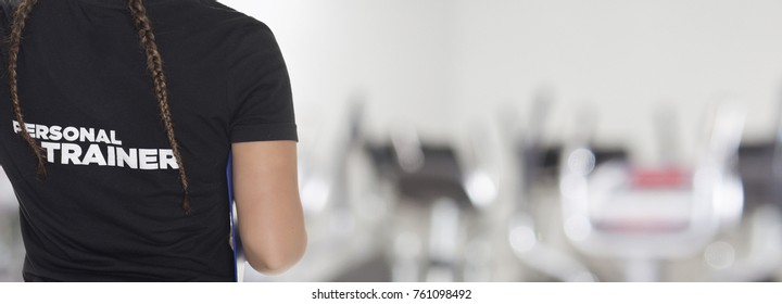 Female Personal Trainer, With His Back Facing The Camera, Looking At A Gym