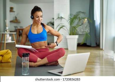 Female personal trainer using computer while holding online exercise class with her clients from home. 