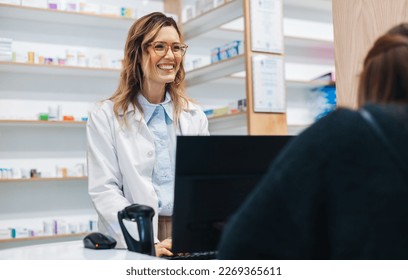 Female pharmacist assisting a patient over the counter in a drug store. Friendly healthcare worker dispensing medication in a pharmacy. - Powered by Shutterstock