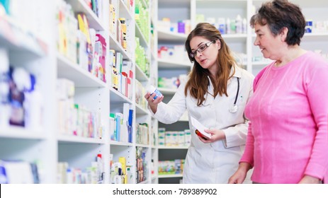 Female pharmacist discusses prescription medication with senior customer at pharmacy