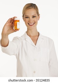 Female Pharmacist Holding Up Bottle Of Pills