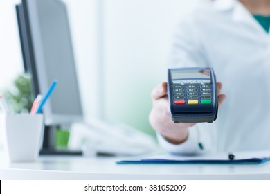 Female Pharmacist Holding A Payment Terminal, Medical Care Cost Concept