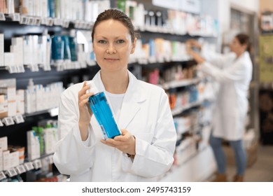 Female pharmacist offers cosmetics products while standing in the trading floor of a pharmacy - Powered by Shutterstock