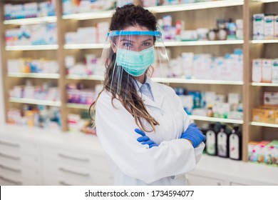 Female Pharmacist With Protective Mask And Face Shield On Her Face ,working At Pharmacy. Medical Healthcare Concept.