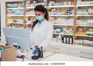 Female pharmacist with protective mask on her face working at pharmacy. Medical healthcare concept. - Shutterstock ID 1734593969