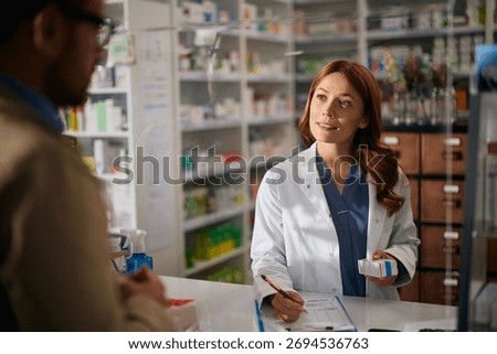 Female pharmacist talking to a man while giving him prescription medicine in a pharmacy. 