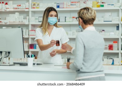 Female Pharmacist Wearing Protective Mask And Serving A Customer Patient In A Pharmacy