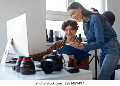 Female photo assistant with checklist and male photographer working together at workplace with computer and equipment, planning photoshoot in studio - Powered by Shutterstock