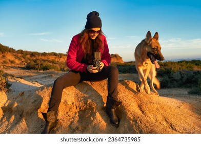 Female photographer capturing her dog with a 6x6 vintage camera in a landscape with a clear sky. With Copy space - Powered by Shutterstock