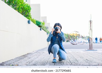 Female Photographer Crouching And Taking Pictures