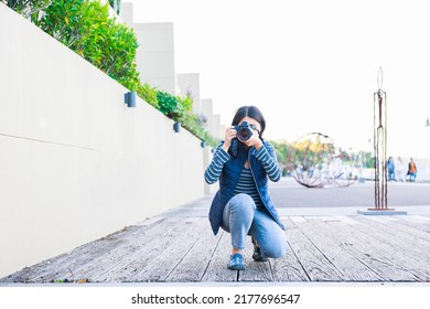 Female Photographer Crouching And Taking Pictures