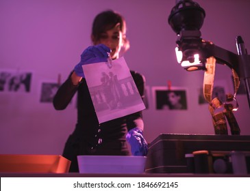 Female photographer developing film and printing photographs in traditional process in darkroom. Portrait of creative girl photographer in photo studio darkroom. Developing analog camera film. - Powered by Shutterstock