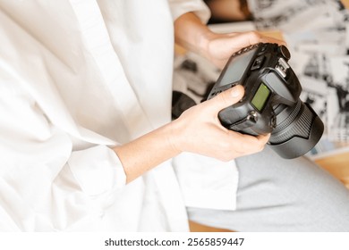 Female photographer reviewing captured images on professional digital camera display in home office, surrounded by photo prints, showcasing photography workflow and image analysis - Powered by Shutterstock