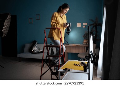 Female photographer setting up camera in home studio. Modern blogger. Content creator. Woman shooting photos. Copy space - Powered by Shutterstock