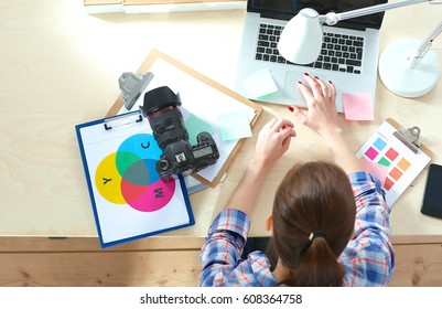 Female photographer sitting on the desk with laptop - Shutterstock ID 608364758
