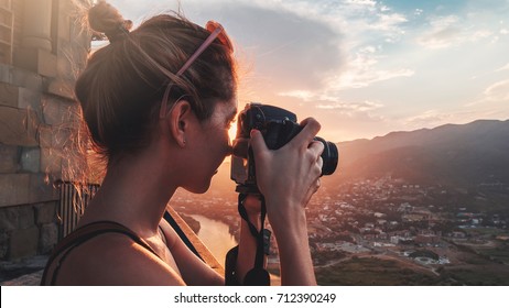 Female photographer, taking pictures of mountain landscape at sunset in Georgia