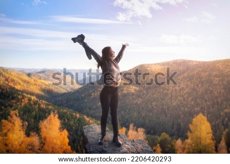 a female photographer at the top of the mountain spread her arms in joy of freedom and space. Landscape shooting of nature and travel concept in autumn