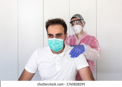 A Female Physical Therapist Is Massaging A Male Client's Chest. She Is Wearing Pink And White Protective Clothing, A Mask And Lilac Latex Gloves To Prevent The Covid-19. Pandemic Virus.