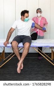 A Female Physical Therapist Is Massaging A Male Client's Chest. She Is Wearing Pink And White Protective Clothing, A Mask And Lilac Latex Gloves To Prevent The Covid-19. Pandemic Virus.