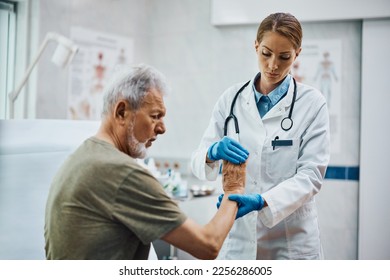 Female physical therapists checking senior patient's hand at medical clinic.  - Powered by Shutterstock