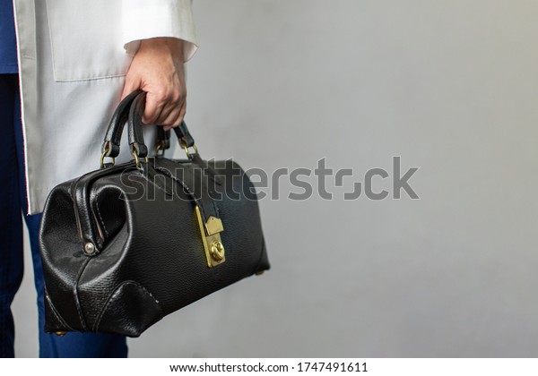 Female physician holding a\
black leather doctor\'s bag heading to the office to practice\
medicine