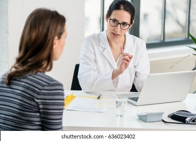 Female Physician Listening To Her Patient During Consultation While Sitting Down In The Office Of A Modern Medical Center