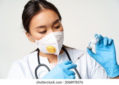 Female Physician, Nurse In Respirator And Sterile Gloves, Filling Syringe With Coronavirus Vaccine, Instert Needle In Covid Vaccination Bottle, White Background