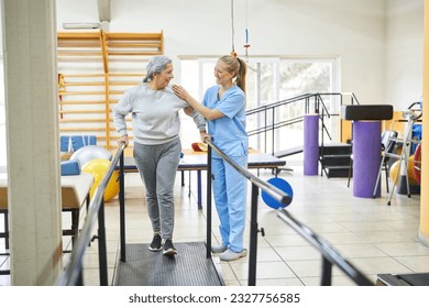 Female physiotherapist assisting happy senior woman in movement therapy at rehab center - Powered by Shutterstock